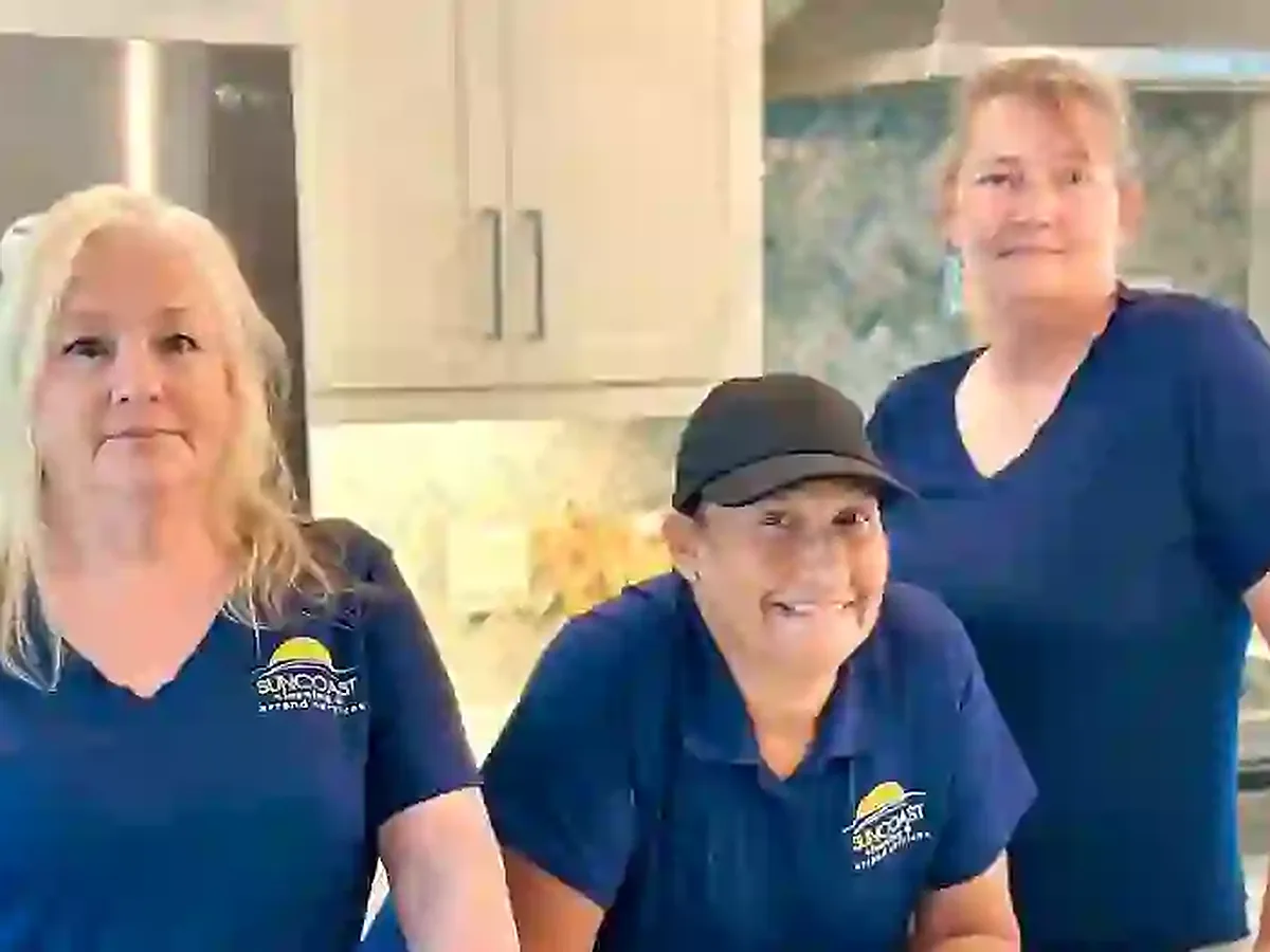 Three members of the Suncoast Cleaning team in branded shirts in a client kitchen