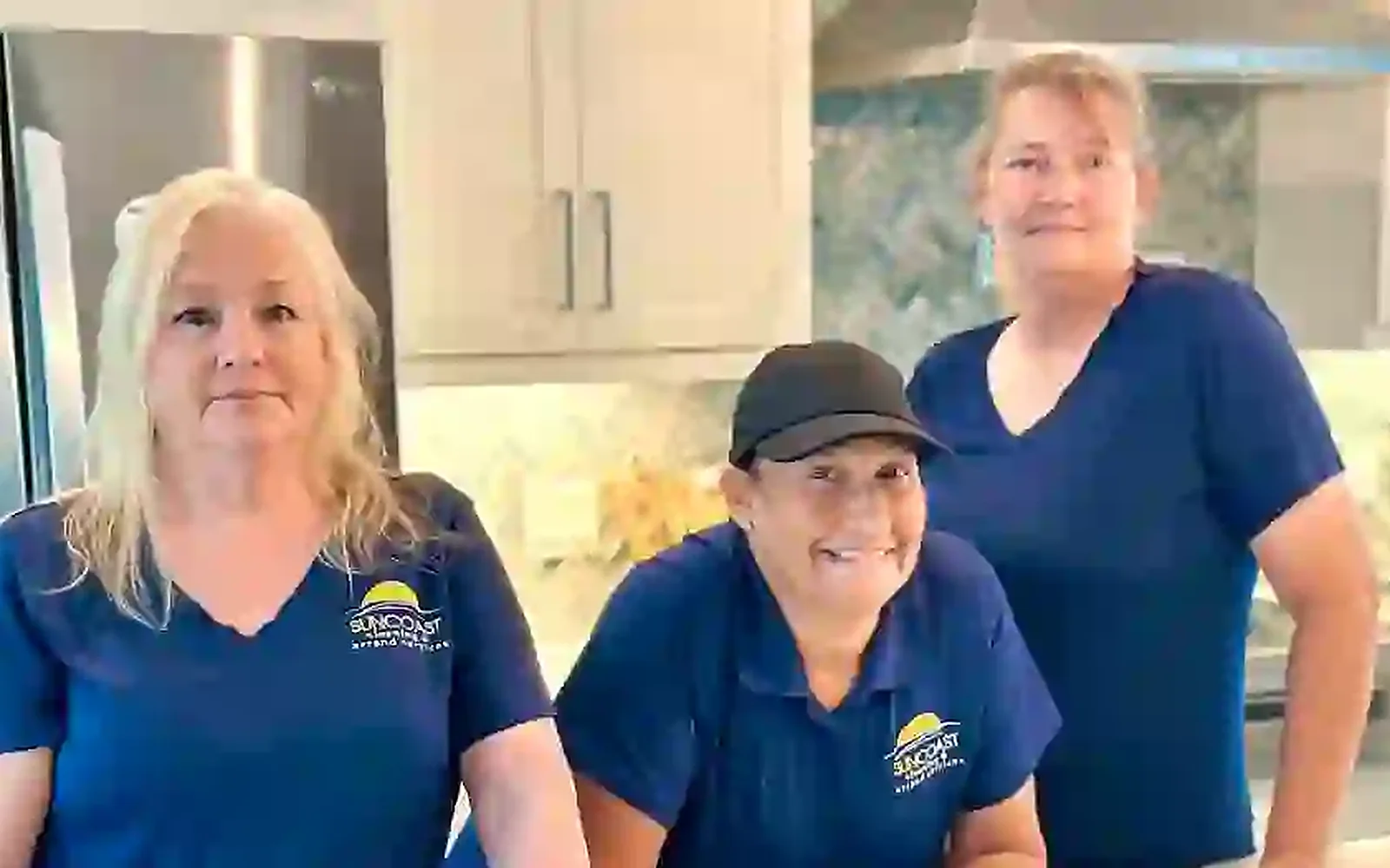 Three members of the Suncoast Cleaning team in branded shirts in a client kitchen